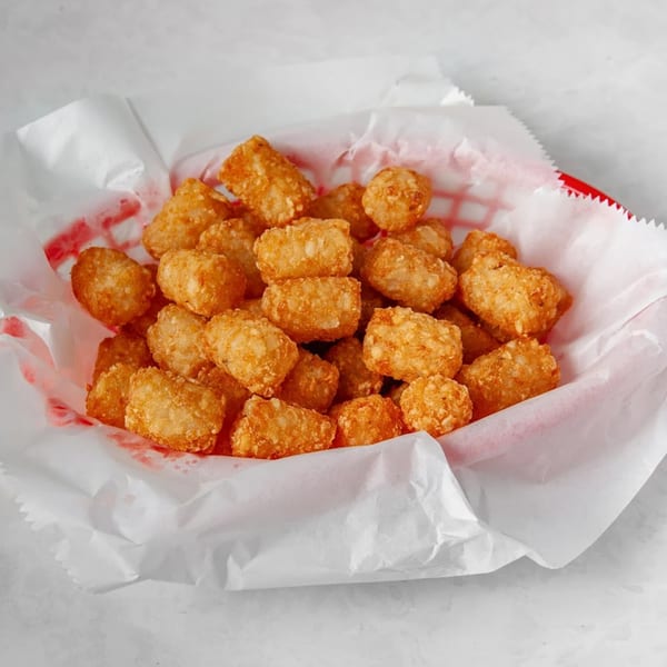 Golden brown tater tots served in a red and white paper-lined basket at Picasso's Sports Café.