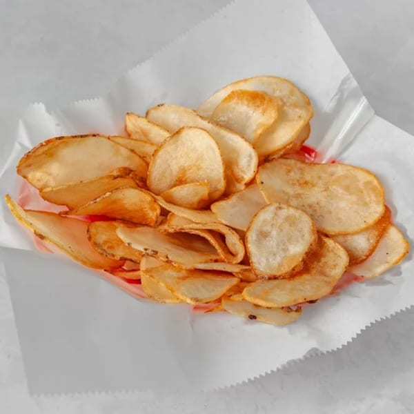 A basket of golden-brown, thinly sliced potato chips, perfect for a sports bar snack.