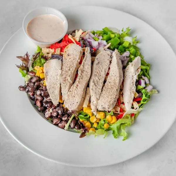 A vibrant Picasso's Sports Café chicken salad with black beans, corn, peppers, and dressing.