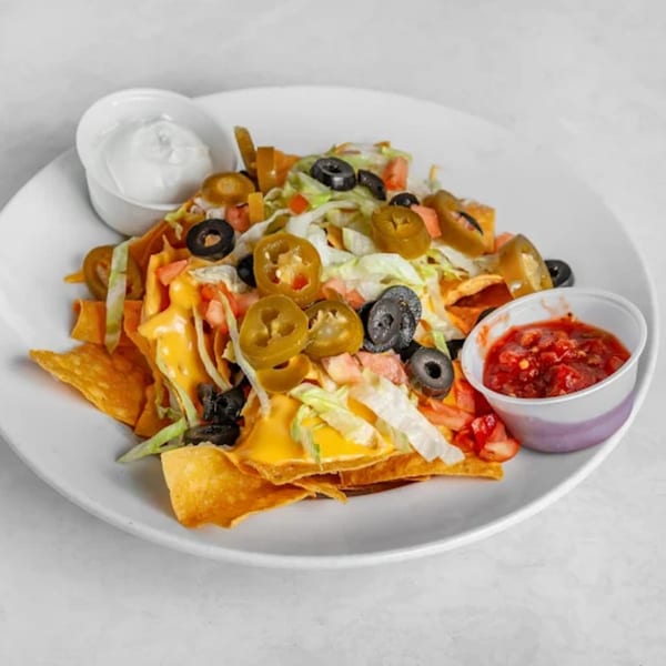 Loaded nachos with melted cheese, jalapeños, black olives, lettuce, tomatoes, salsa, and sour cream.